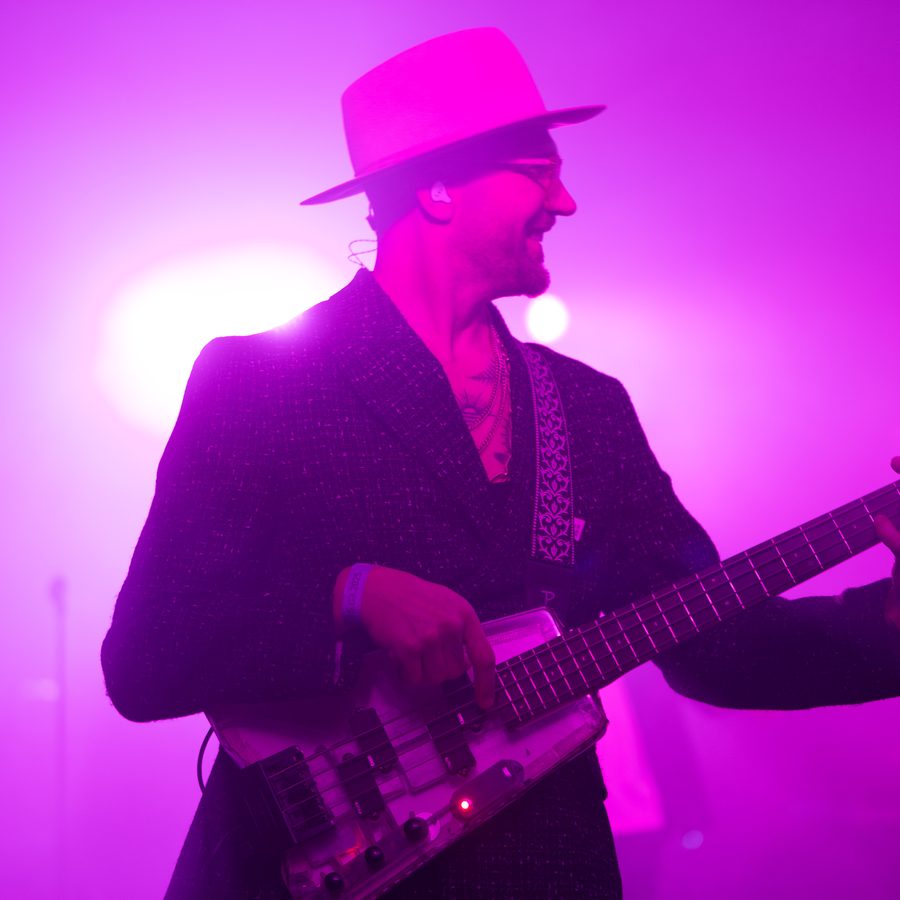 Guitarist performing on stage with pink and purple stage lighting, photographed by Pixer