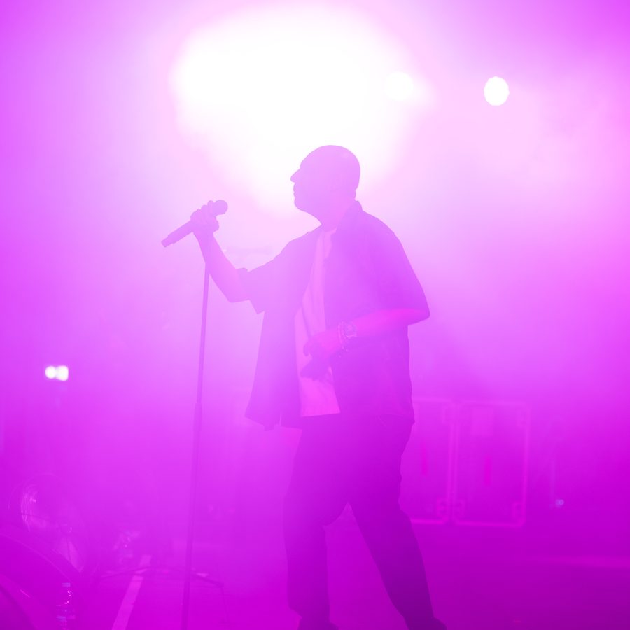 Performer silhouette on stage with vivid purple lighting, photographed by Pixer