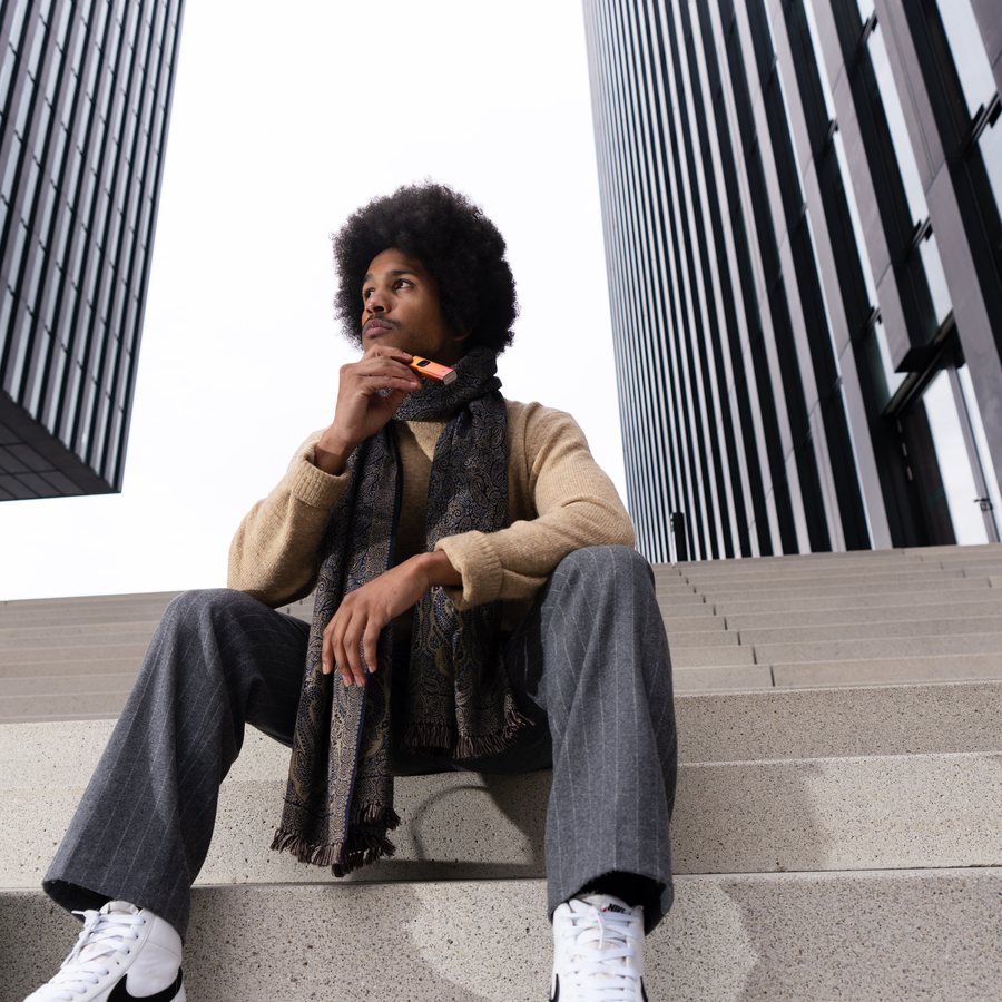 Lifestyle product photography — man sitting on steps at modern architecture, urban outdoor shoot